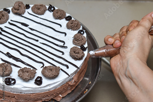 applying chocolate cream on vaniila cake with cake nozzel photo