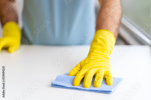 Close up of male housekeeper specialist hold blue duster cleaning table perform housekeeping job service, man make daily house chores dust off using cloth
