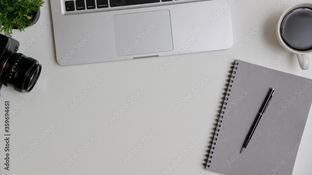 Modern white office desk table with laptop computer, a notebook and cup of coffee. Top view with copy space, flat lay. Modern white office desk table with laptop computer, a notebook and cup of coffee. Top view with copy space, flat lay.