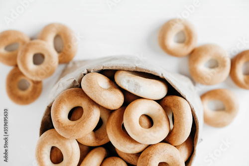 Drying or round bagels in a paper bag on a white wooden background. Top view. Copy, empty space for text