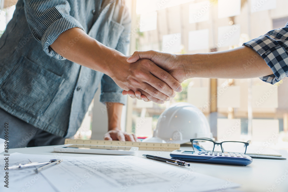 Architect and engineer construction workers shaking hands after success collaboration