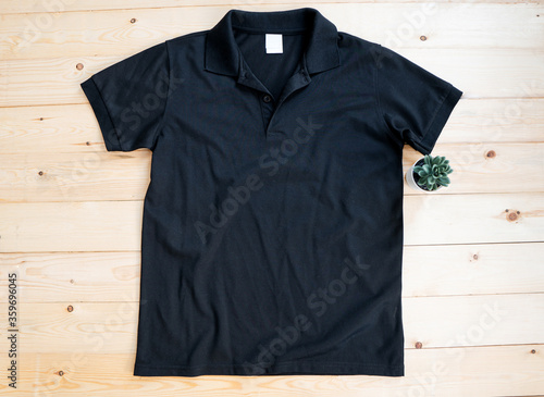 Black male Polo shirt mock up flat lay on wooden background. Top front view