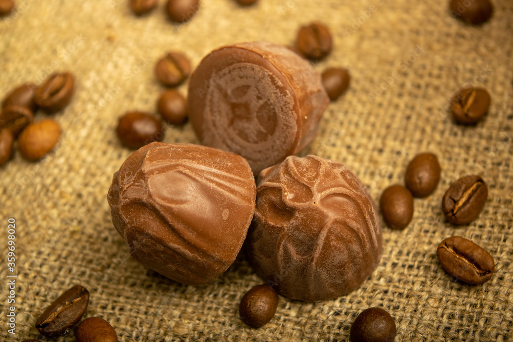 Chocolate, coffee beans and chunks of brown cane sugar on a background of homespun fabric with a rough texture. Close up.