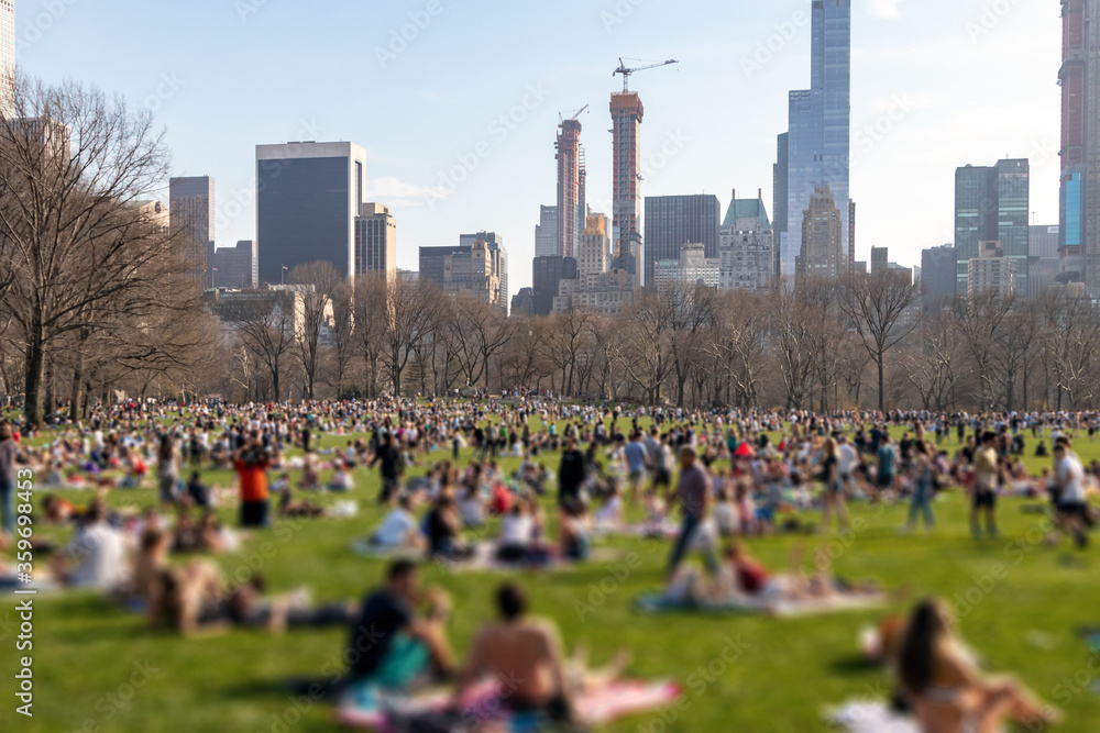 Blurred crowds of people relaxing on the lawn in Central Park on a sunny day in New York City