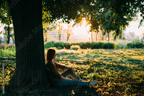 girl sitting near a tree at sunset
