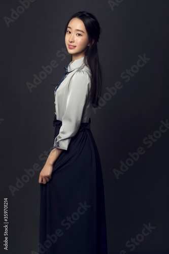 Young beautiful Asian female college student in black background