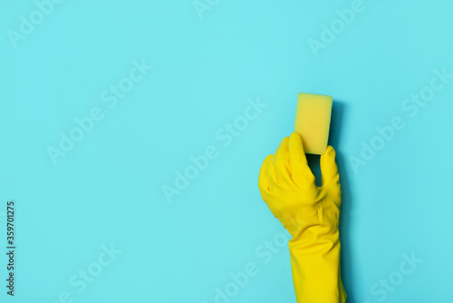 Hand in glove holding microfiber cleaning cloth, sponge on blue background. Copy space. Cleaning service concept. Spring general or regular clean up. Commercial cleaning company concept.