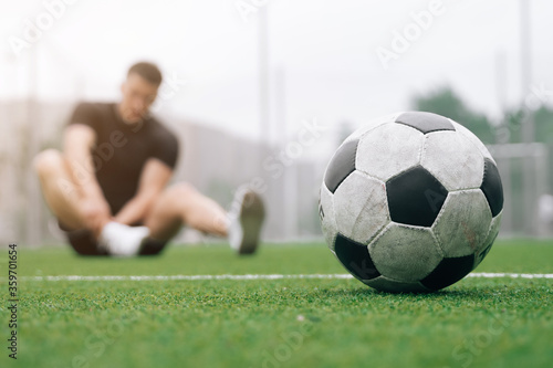 soccer player A man holds his foot. focus on the soccer ball. Dislocation or sprain of the joint.