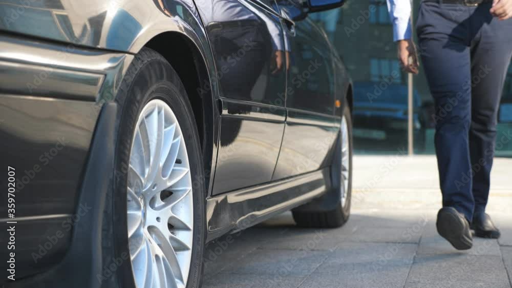 Driver coming to the car and opens the door for the businessman. Chauffeur uncover door of automobile for male passenger. Business man get out from the auto and leaves to office building. Slow Motion Driver coming to the car and opens the door for the businessman. Chauffeur uncover door of automobile for male passenger. Business man get out from the auto and leaves to office building. Slow Motion