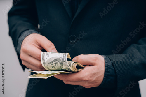man in black counts dollars in hands
