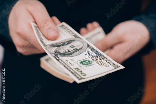 man in black holds out one hundred dollar bill 