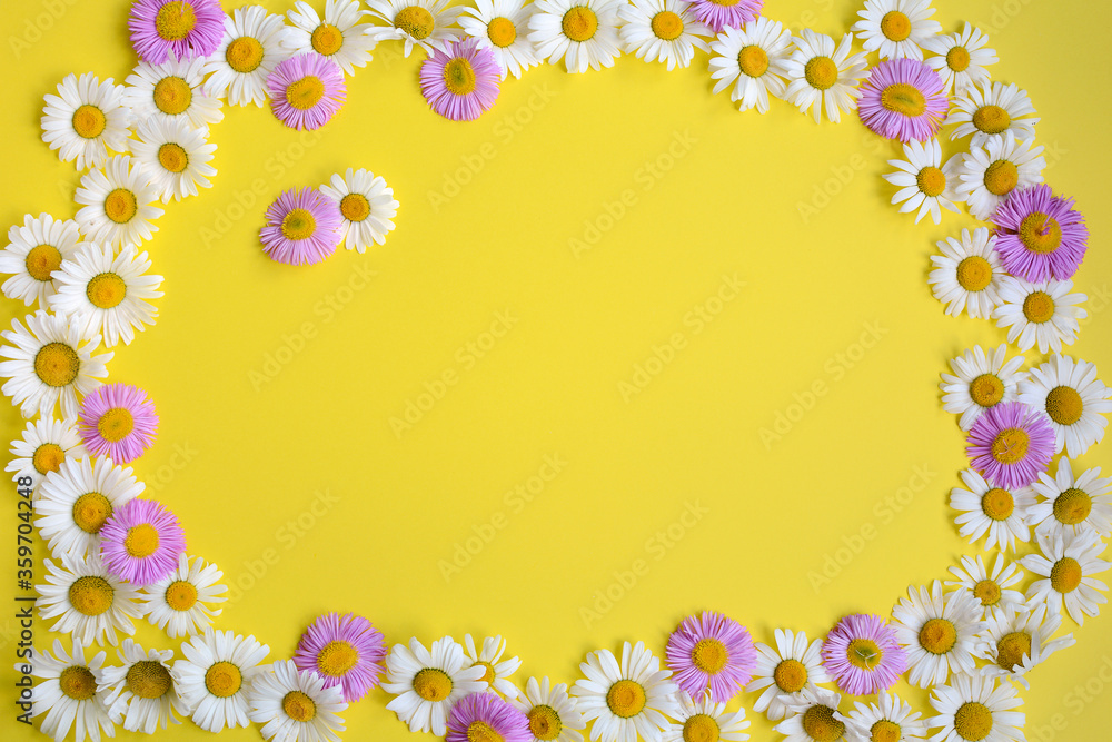 Obraz premium Arrangement of daisy flowers and pink flowers on a yellow background with a central space for design. Top view