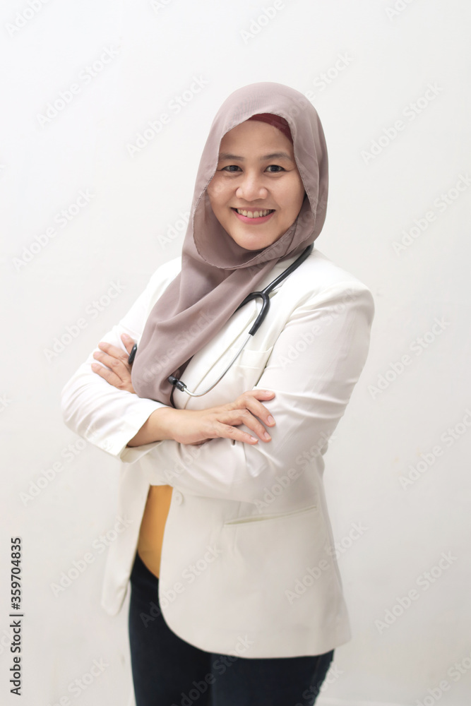 Muslim female doctor wearing hijab and suit, standing with crossed arm and holding stethoscope, succesful confident person Muslim female doctor wearing hijab and suit, standing with crossed arm and holding stethoscope, succesful confident person