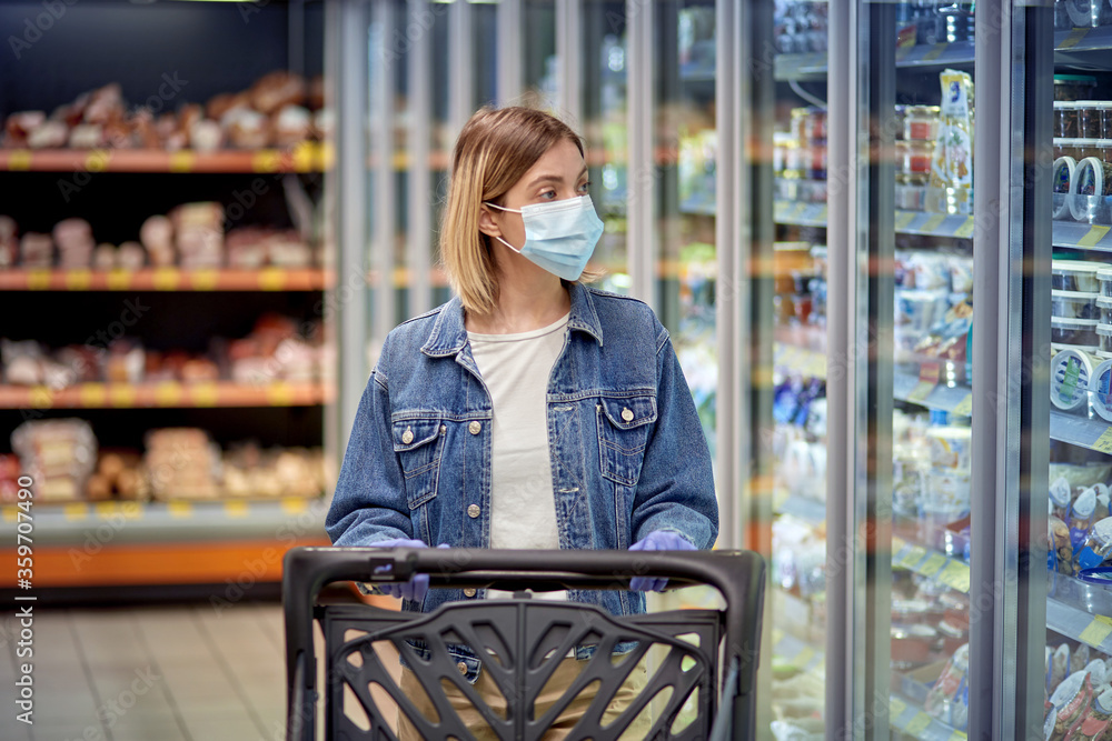 Beautiful girl in the store chooses products. Woman in a medical mask and gloves