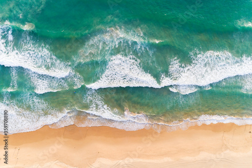 Aerial view sandy beach and crashing waves on sandy shore Beautiful tropical sea in the morning summer season image by Aerial view drone shot, high angle view Top down. © panya99