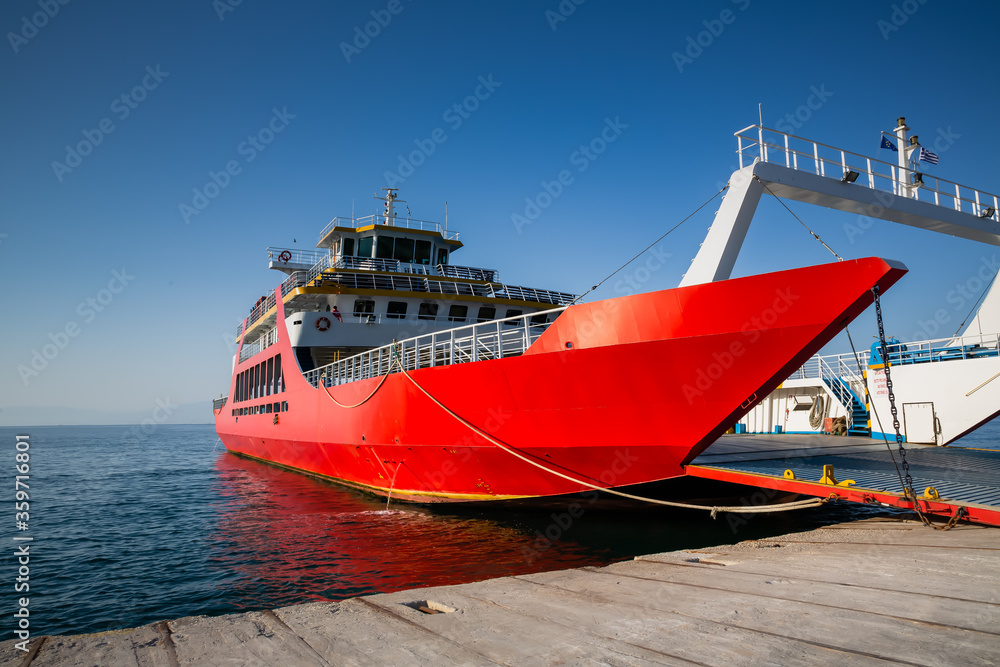 Red ferry boat with an open ramp and empty car deck, moored to the harbour, Thassos Island, Greece