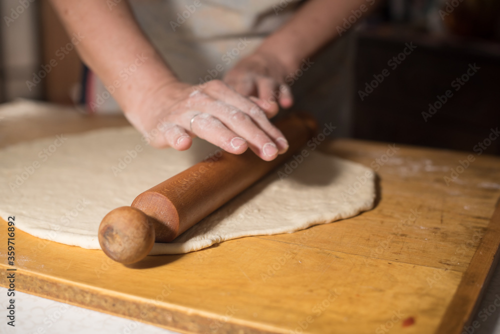 preparing  dough for baking with hands and roler 