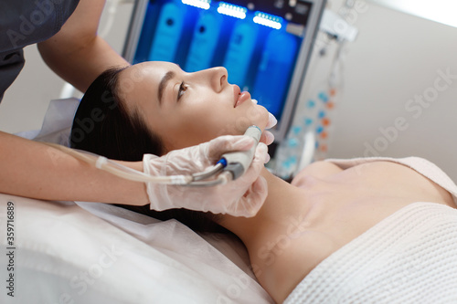 Professional female cosmetologist doing hydrafacial procedure in Cosmetology clinic.