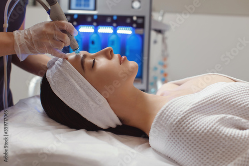 Side view of woman receiving microdermabrasion therapy on forehead at beauty spa photo