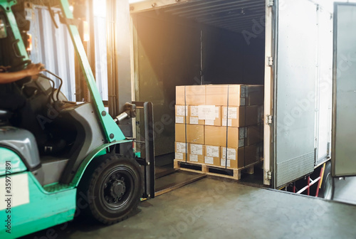 Tableau sur toile Workers Driving Forklift Tractor Loading Cargo Pallets into Container Trucks