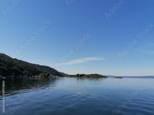 Beautiful calm day on the sea with clear blue sky and island with pine trees photo