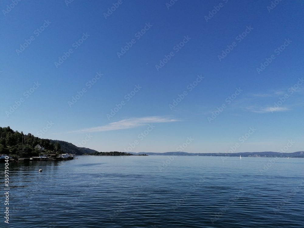 Beautiful calm day on the sea with clear blue sky and island with pine trees Beautiful calm day on the sea with clear blue sky and island with pine trees