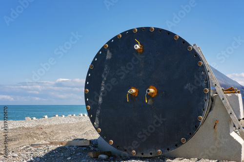 A locked large plastic pipeline on the coast with blue sea background photo