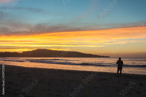 sunset at the beach with silhouette of a man