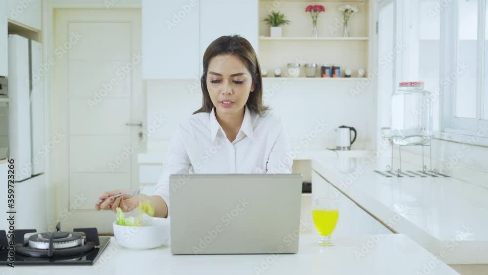 Businesswoman works with laptop while eating salad Businesswoman works with laptop while eating salad