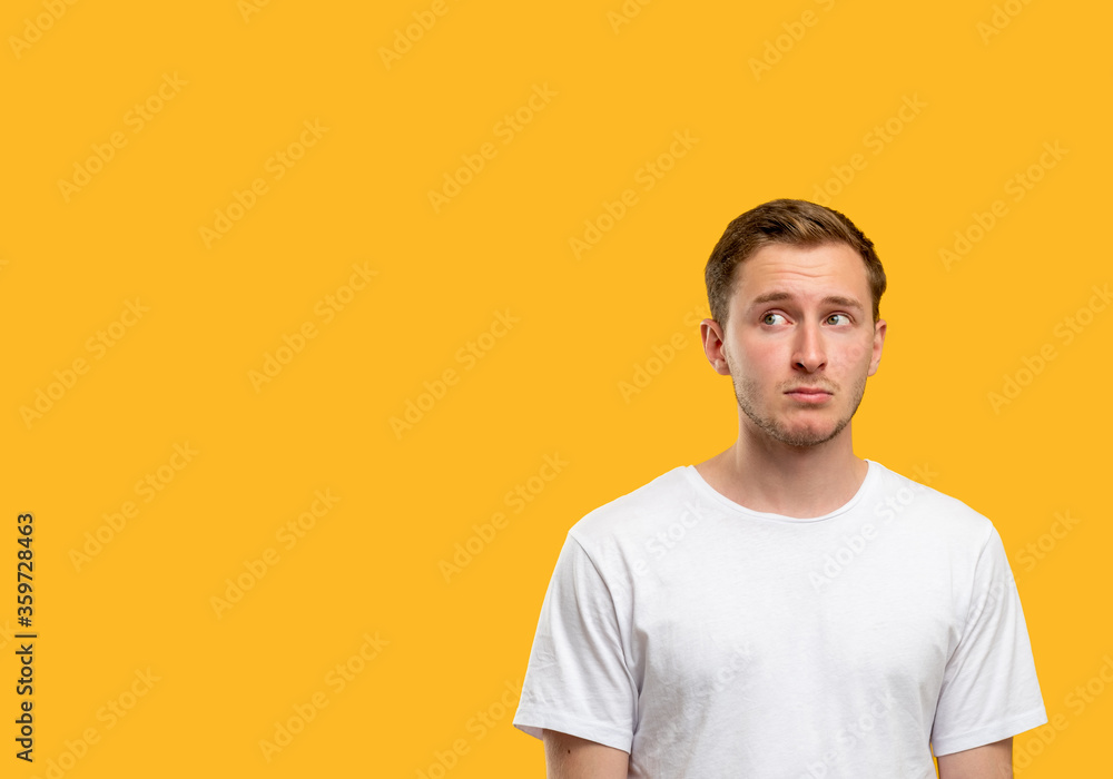 Confused man portrait. Announcement background. Doubtful guy isolated looking curiously at orange copy space.