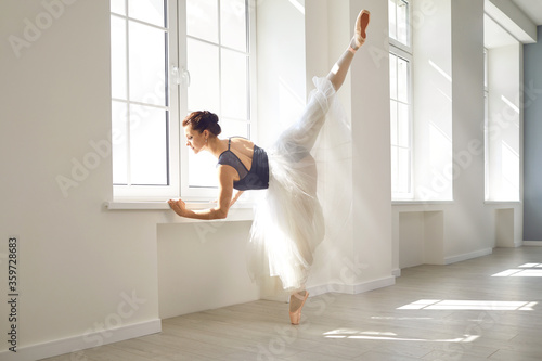 Ballerina. Young graceful ballet dancer is rehearsing a performance in a white class studio