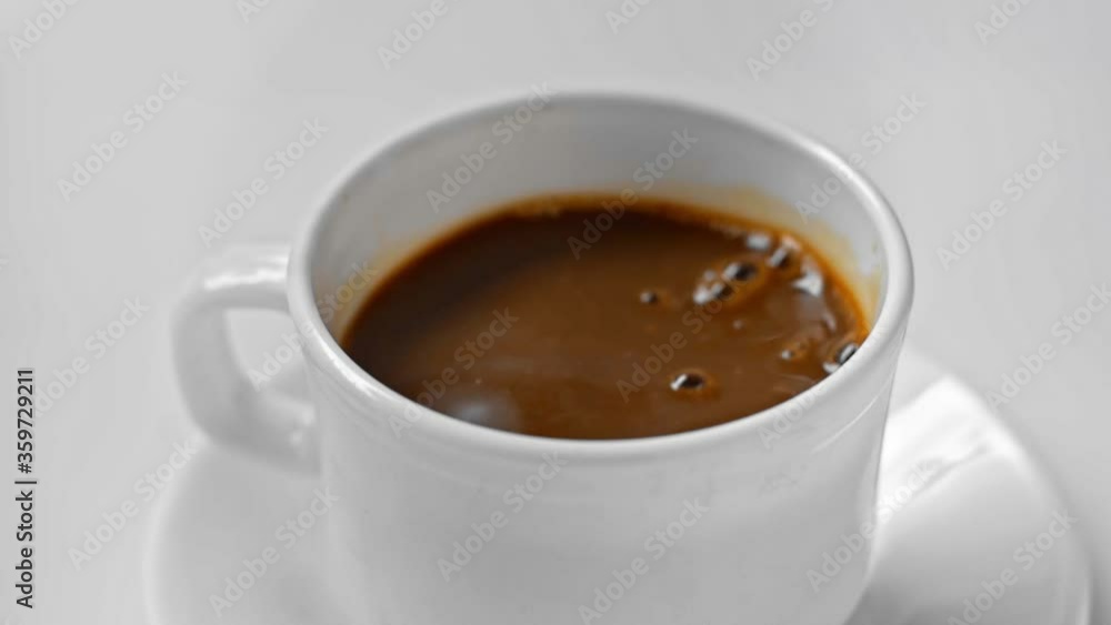 Slow-motion of sugar cubes pouring in coffee isolated on white Slow-motion of sugar cubes pouring in coffee isolated on white