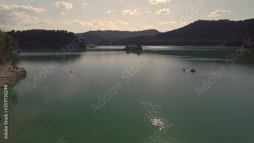 El Chorro peaceful mountain valley lake island shimmering water reflection aerial pull back view