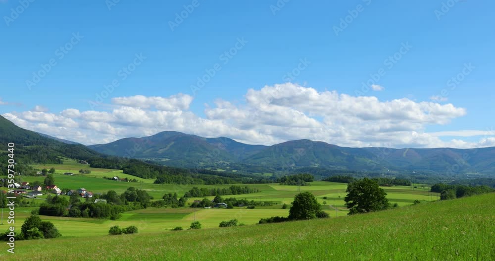 The peaks of hills and mountains lie against the backdrop of the Beskydy countryside around the village of Kozlovice with a sky full of clouds moving grass in a strong wind. The peaks of hills and mountains lie against the backdrop of the Beskydy countryside around the village of Kozlovice with a sky full of clouds moving grass in a strong wind.