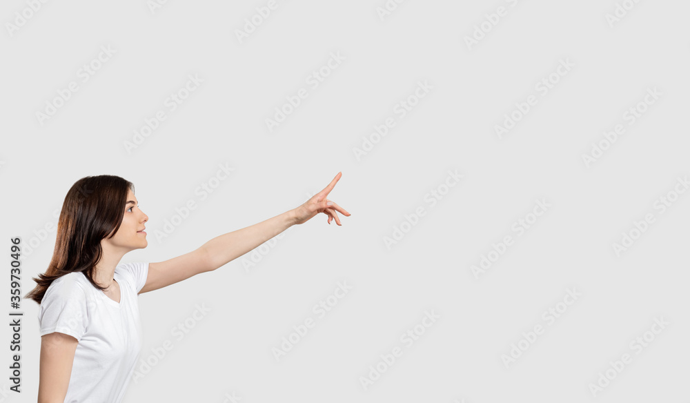 Promotional background. Ad message. Curious woman isolated pointing up at neutral copy space. Promotional background. Ad message. Curious woman isolated pointing up at neutral copy space.
