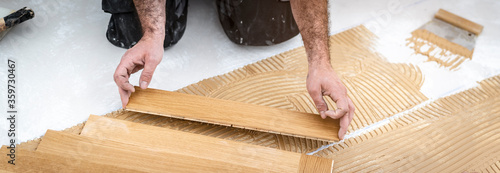 ein talentierter Parkettleger Meister verlegt einen neuen Holzboden und setzt gerade ein Stück Eichenboden an 