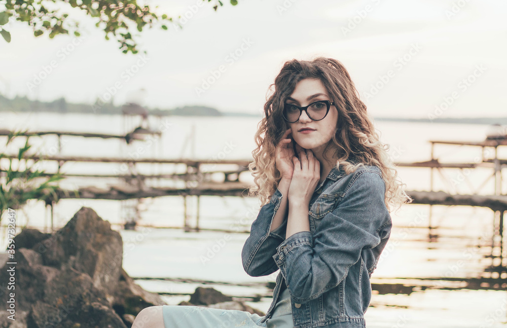 
Portrait of a girl in glasses on the beach near the river