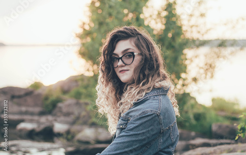 Portrait of a girl in glasses near the sea at sunset