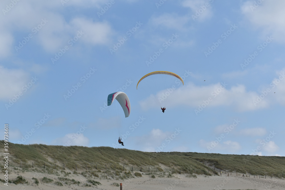 Paragliding at the beach of Katwijk aan Zee. Paraglider's making use of updraft of the dunes to stay in the air Paragliding at the beach of Katwijk aan Zee. Paraglider's making use of updraft of the dunes to stay in the air