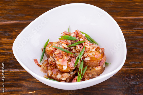 Potatoes in uniform, served with bacon and fresh green onions 