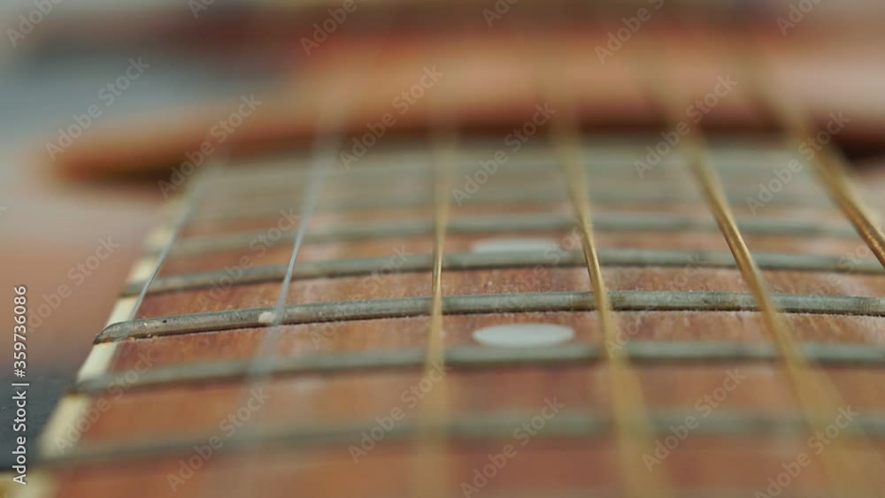 Closeup detail of steel guitar strings and frets for making music. Guitar neck in selective focus.