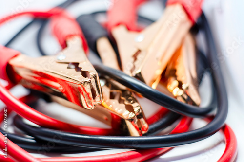Close up of red and black car battery jumper cable, isolated on white background. Boost cable. Focus on metal
