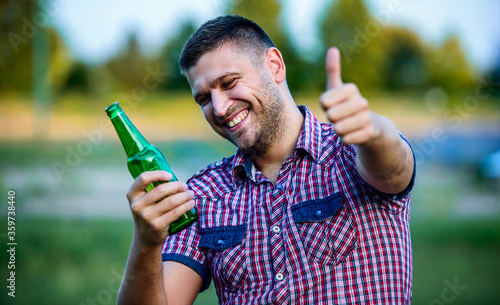 Man drinking beer and showing thumb up