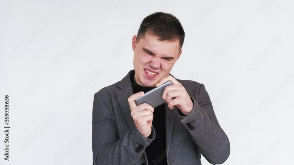 Online fun. Mobile app. Excited business man enjoying playing video game on smartphone isolated on white. Online fun. Mobile app. Excited business man enjoying playing video game on smartphone isolated on white.