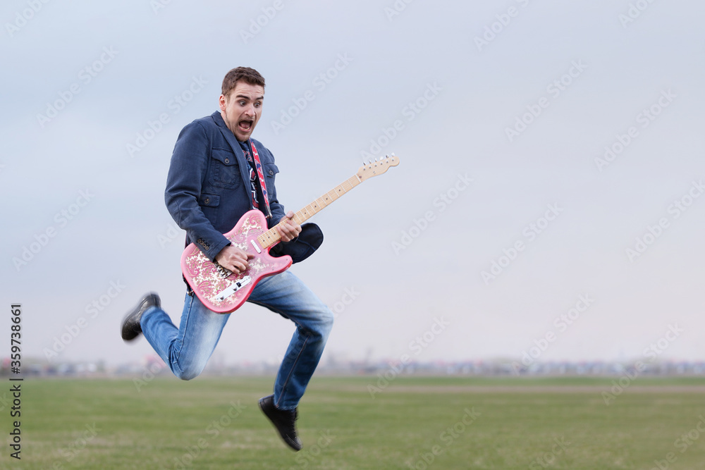 Guitar hipster guy jumping and playing funky rock music outdoors Guitar hipster guy jumping and playing funky rock music outdoors