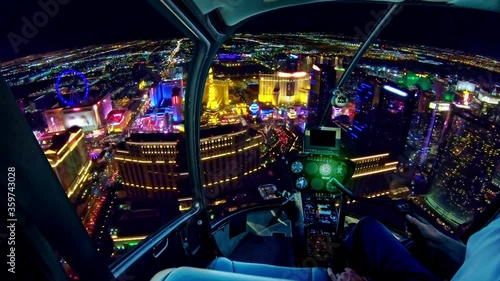 Helicopter interior on Las Vegas buildings and skyscrapers of downtown with illuminated casino hotels at night. Scenic flight above Vegas skyline by night in the Nevada United States of America.