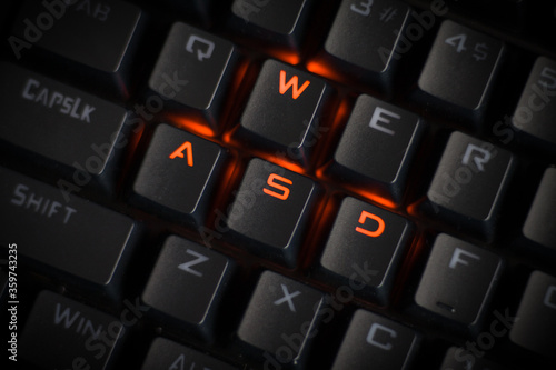 WASD keys light up in orange on RGB mechanical gaming keyboard. WASD keys used for walking in games