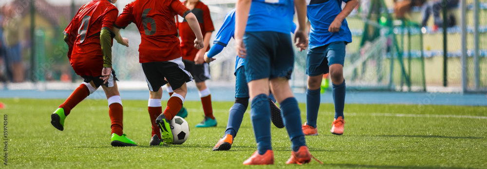 Sporty Football Boys Running After Ball in Duel. Horizontal Football Background. School Soccer Competition Between Junior Level Players. Multi-ethnic Kids Play Sports Sporty Football Boys Running After Ball in Duel. Horizontal Football Background. School Soccer Competition Between Junior Level Players. Multi-ethnic Kids Play Sports
