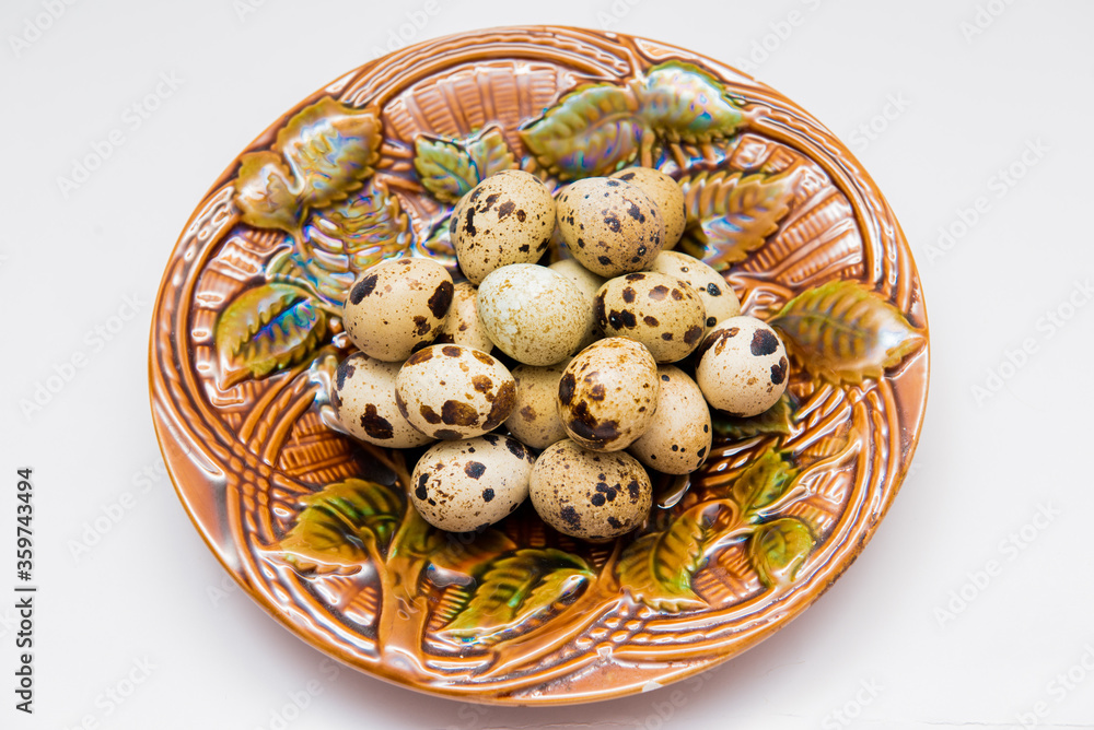 Quail eggs lie on a vintage plate with patterns on a white background