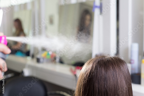 the hairdresser uses hair spray, spraying on flawless hair. In the beauty salon. Beauty and health hair care, thermal protection for hair with a spray, hair spray